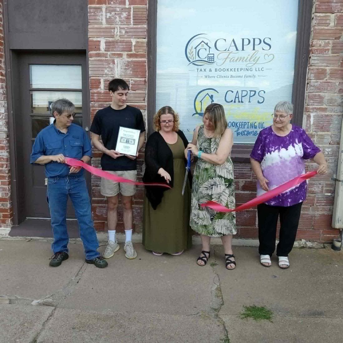 Philip and Sherri Capps and their family hold the grand opening ribbon in front of the Capps Family Tax and Bookkeeping storefront window.